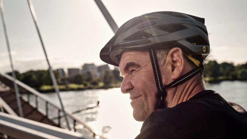 JobRadler auf Fahrradbrücke fährt grinsend in den Feierabend