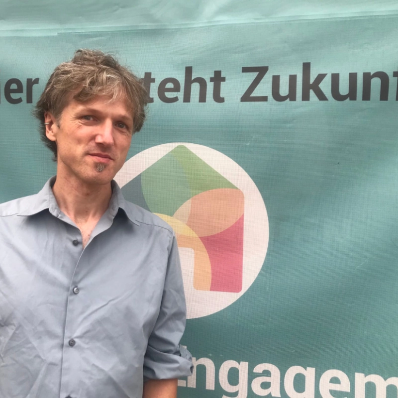Philipp Bedall vor einem Plakat des Haus des Engagements e. V.